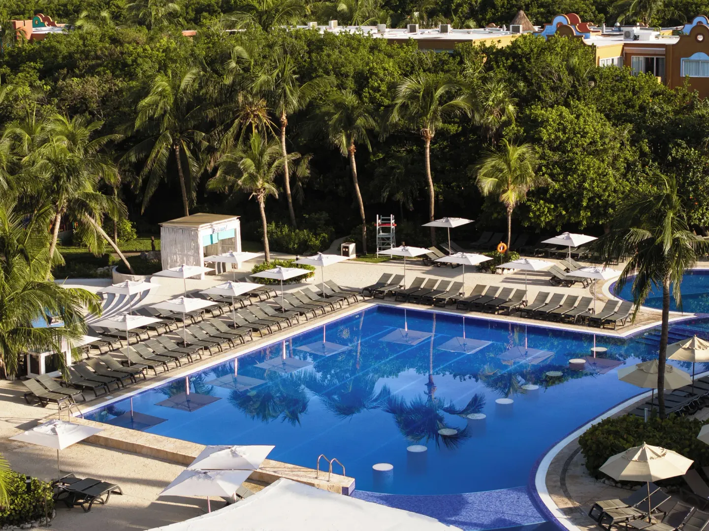 Aerial view of the main pool and palm-lined sundeck at Catalonia Playa Maroma.