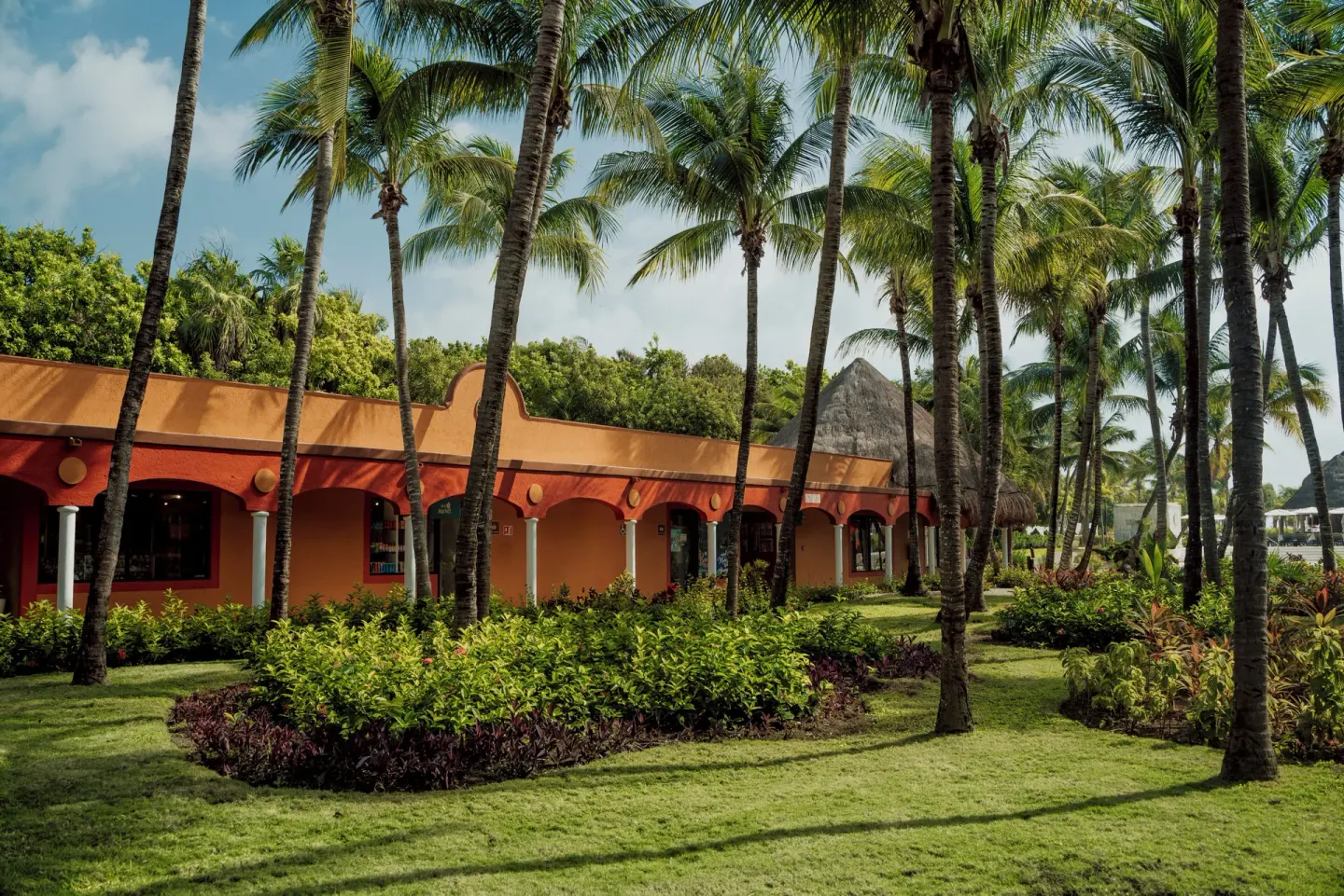 Palm-lined orange resort building and gardens at Catalonia Playa Maroma.