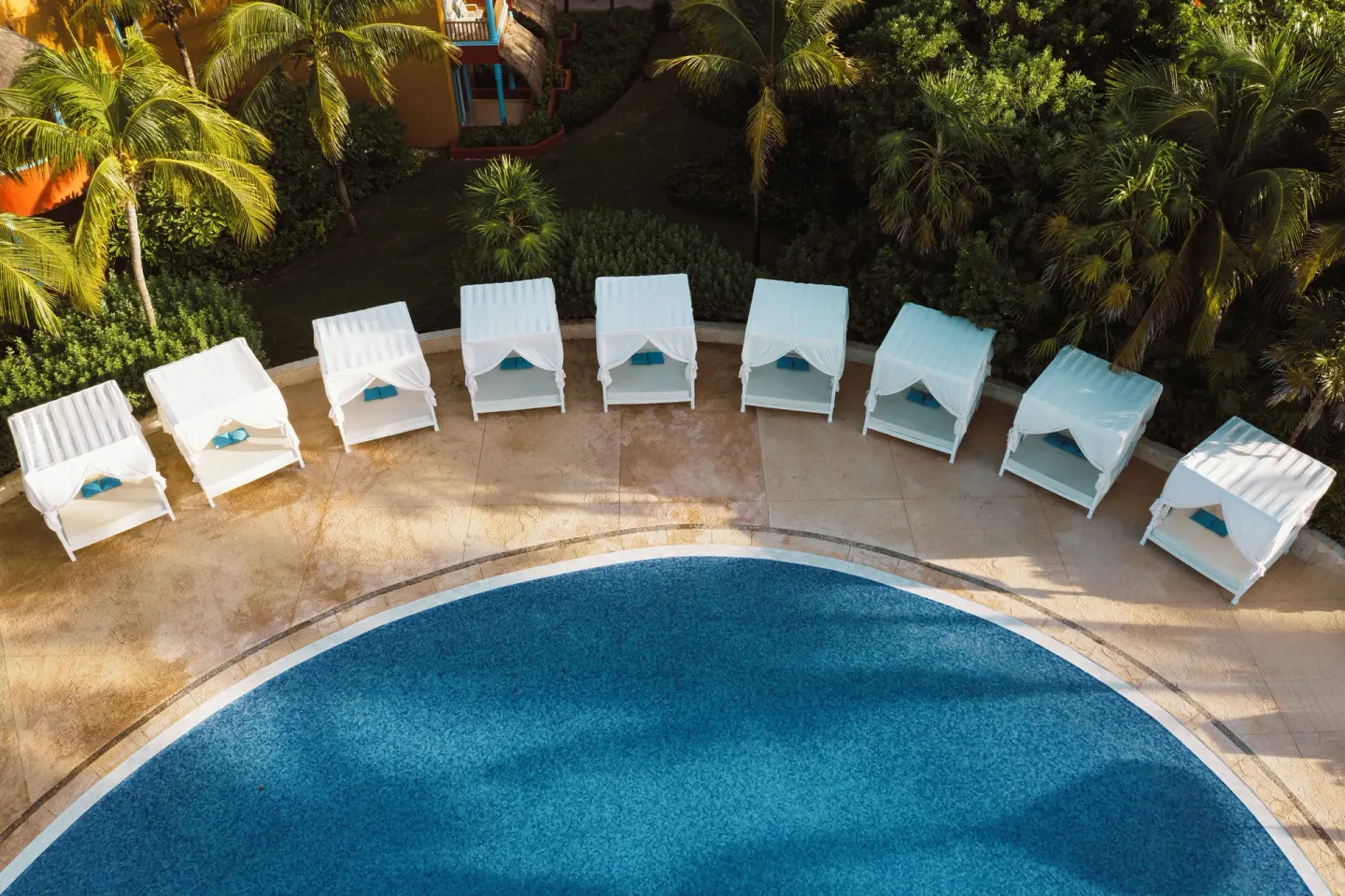 Poolside white daybeds beside a curved pool at Catalonia Playa Maroma.