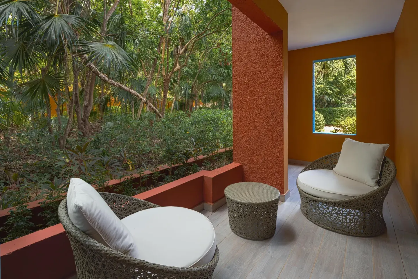 Private terrace with woven lounge chairs and garden view at Catalonia Playa Maroma.