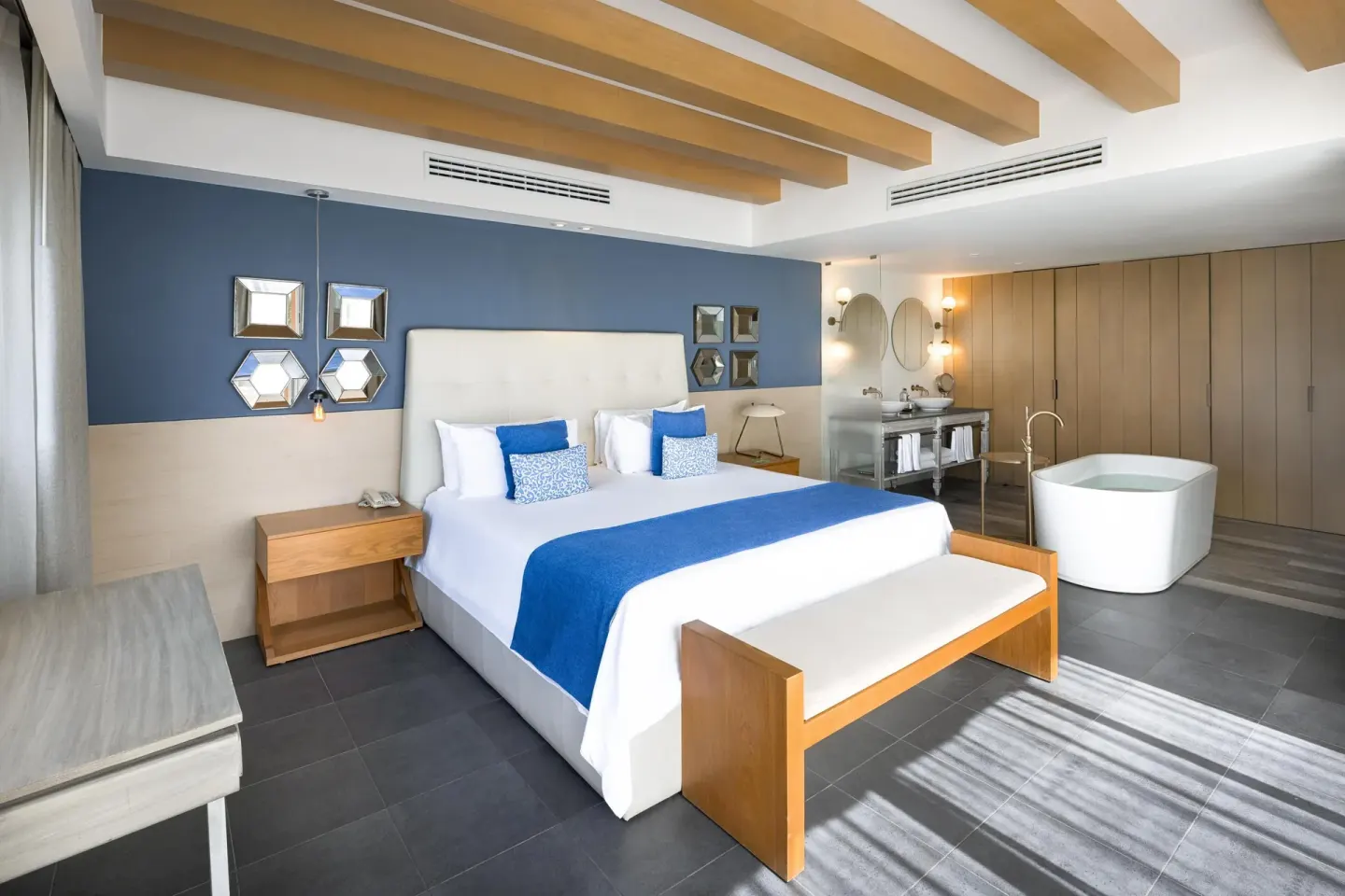 Spacious suite with king bed, soaking tub and blue accent wall at Catalonia Playa Maroma.