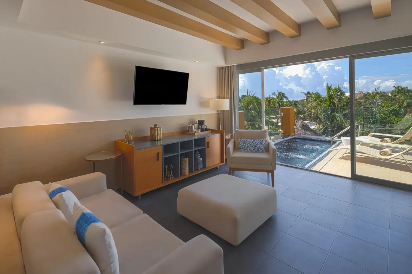 Suite living area with sofa, TV and terrace plunge pool at Catalonia Playa Maroma.