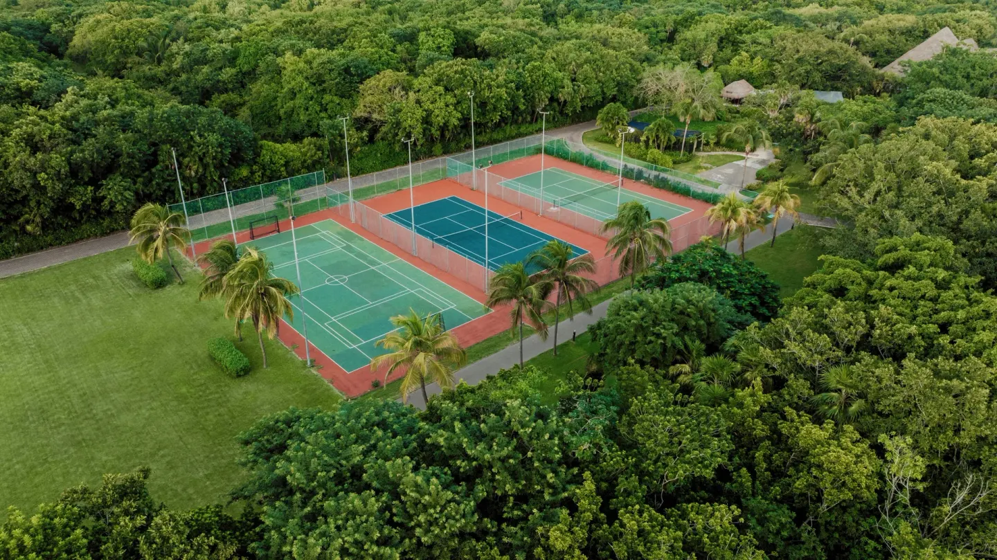 Aerial view of tennis courts surrounded by forest at Catalonia Playa Maroma.