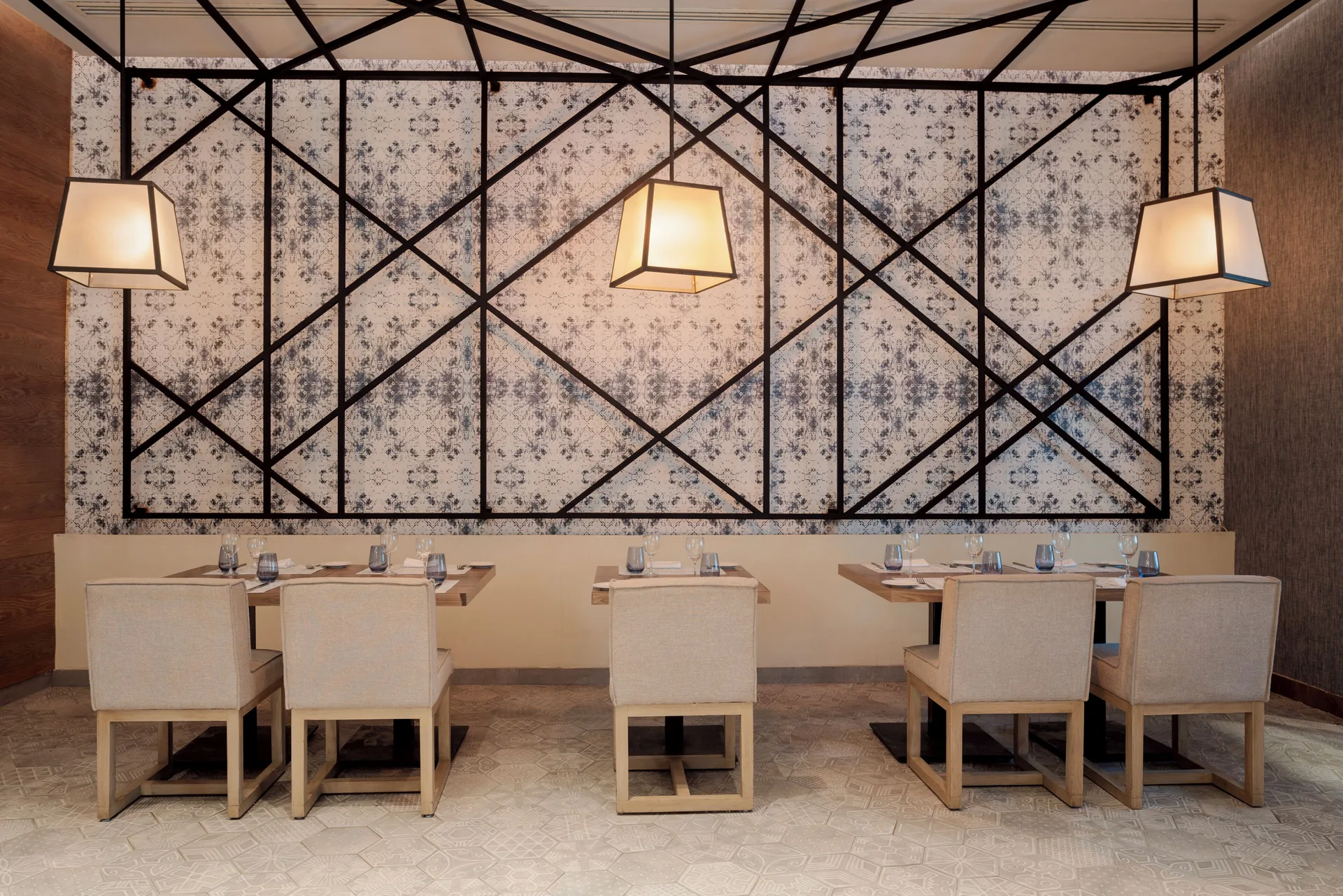 Restaurant tables beneath geometric wall panels at Catalonia Playa Maroma.