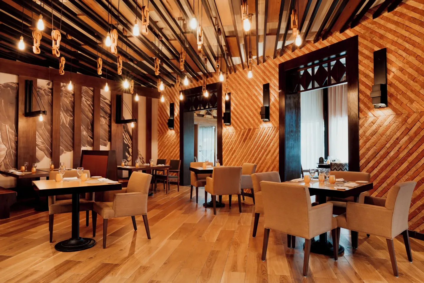Warm wood dining room with pendant lights at Catalonia Playa Maroma.