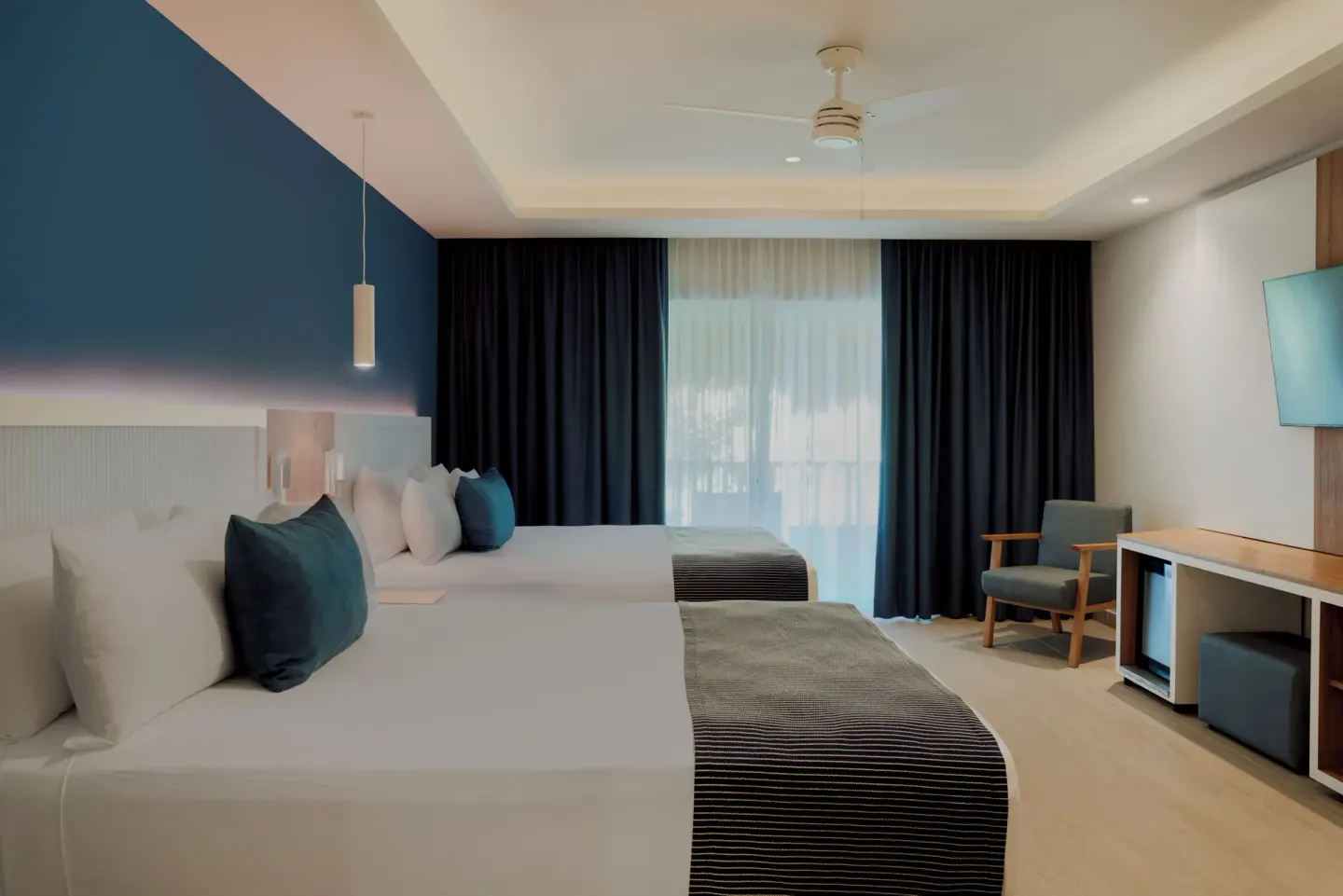 Premium Deluxe Room with two beds, curtains and desk area at Catalonia Playa Maroma.