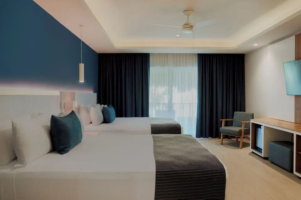Premium Deluxe Room with two beds, curtains and desk area at Catalonia Playa Maroma.