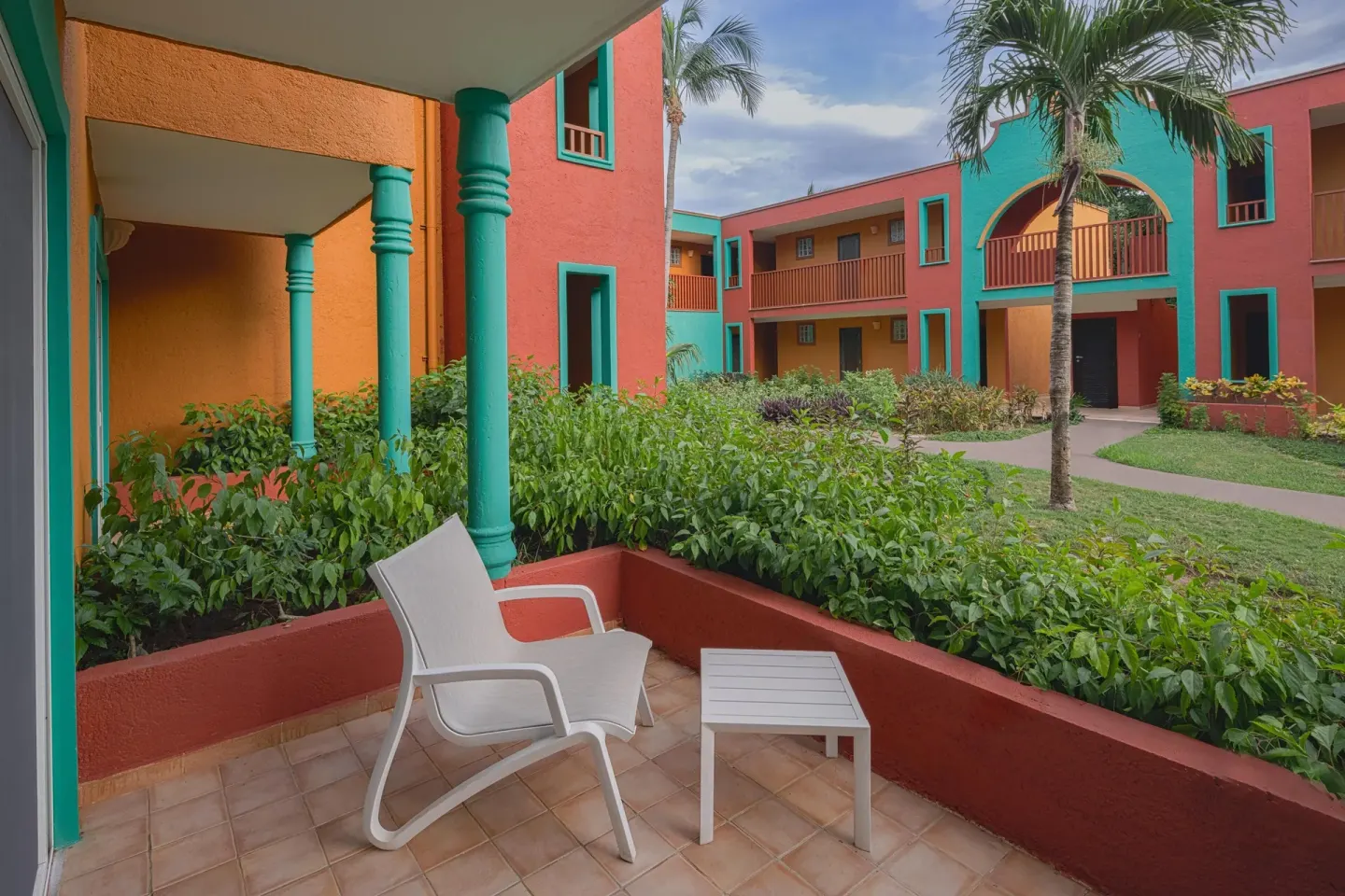 Premium Room patio with chair, table, and garden courtyard at Catalonia Playa Maroma.