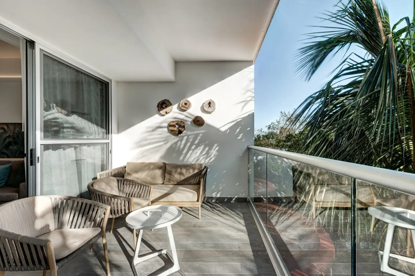 Privileged Suite balcony with sofa, chairs, and palm greenery at Catalonia Playa Maroma.