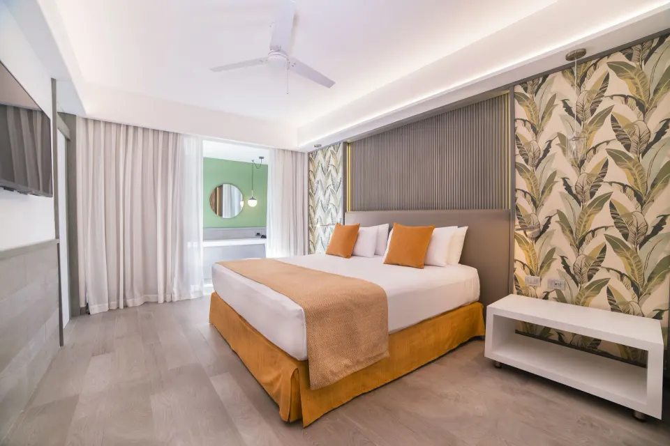 Privileged Suite bedroom with king bed and leafy wallpaper at Catalonia Playa Maroma.