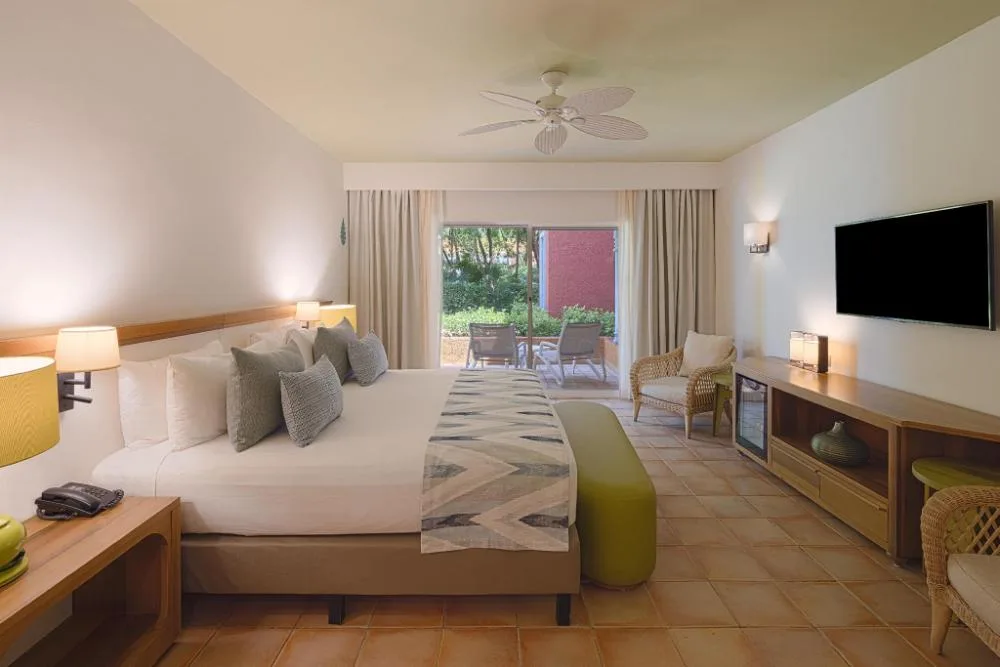 Privileged Superior Room with king bed, TV console, and patio doors at Catalonia Playa Maroma.