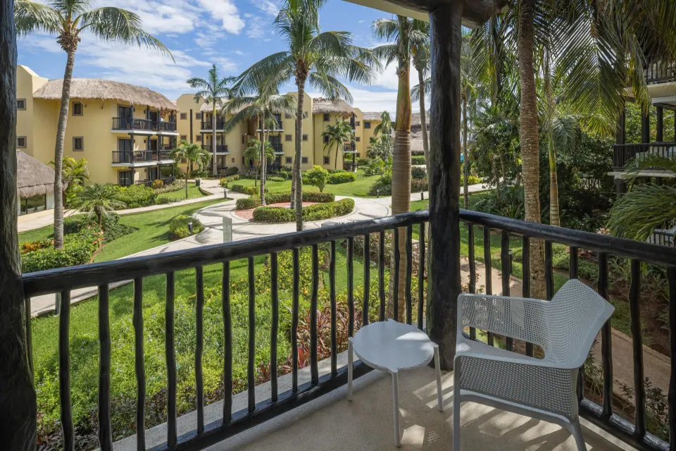 Balcony with chairs overlooking resort courtyards and palm trees at Catalonia Riviera Maya Resort and Spa