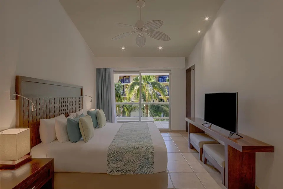 King-bed room with balcony view of palm trees and TV cabinet at Catalonia Riviera Maya Resort and Spa