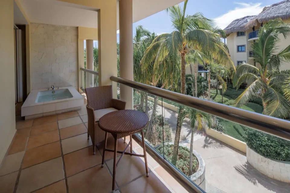 Private balcony with table, chairs and outdoor tub overlooking palms at Catalonia Riviera Maya Resort and Spa