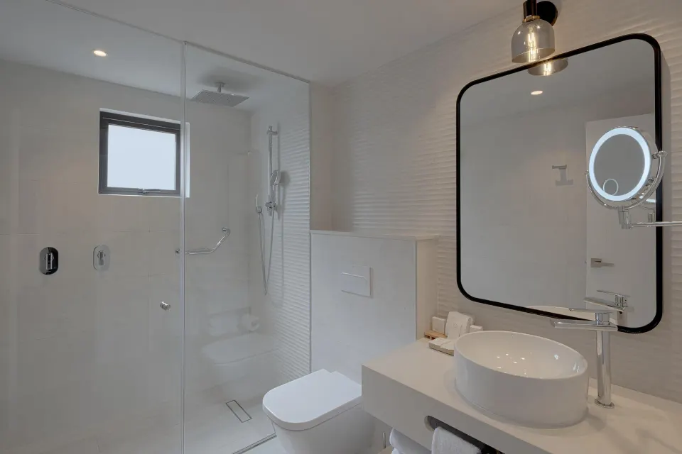 Bright white bathroom with glass shower and round vessel sink at Catalonia Riviera Maya Resort and Spa