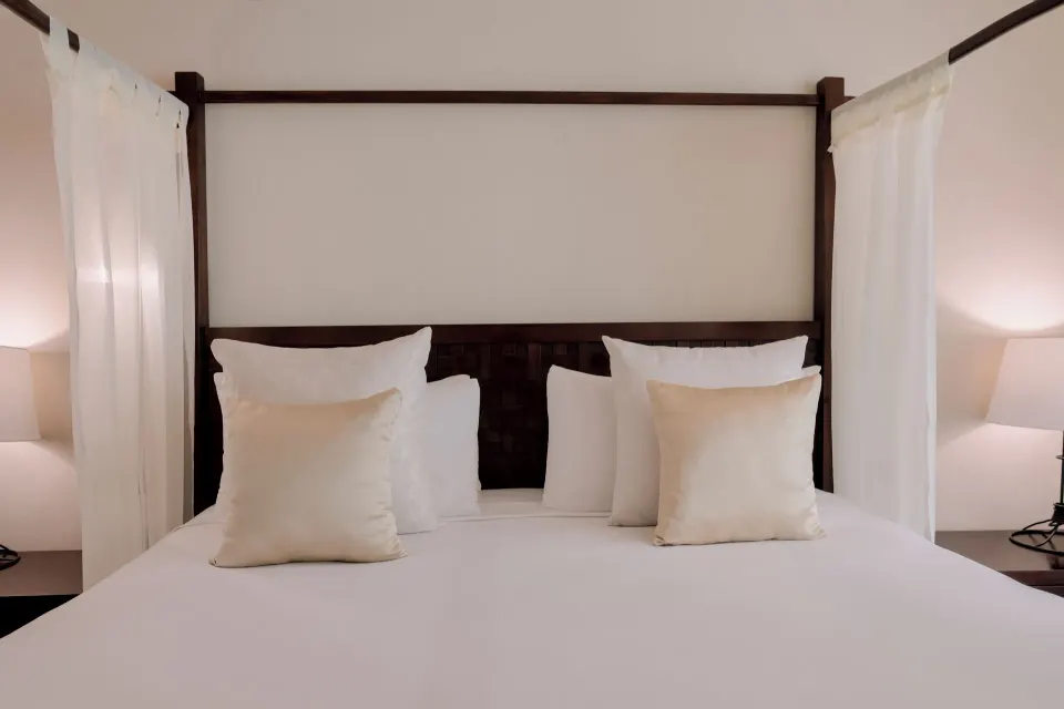 Head-on view of a four-poster bed with pillows at Catalonia Riviera Maya Resort and Spa