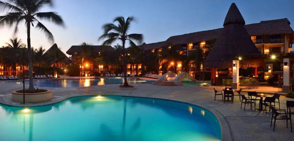 Evening view of illuminated pools and resort buildings at Catalonia Riviera Maya Resort and Spa