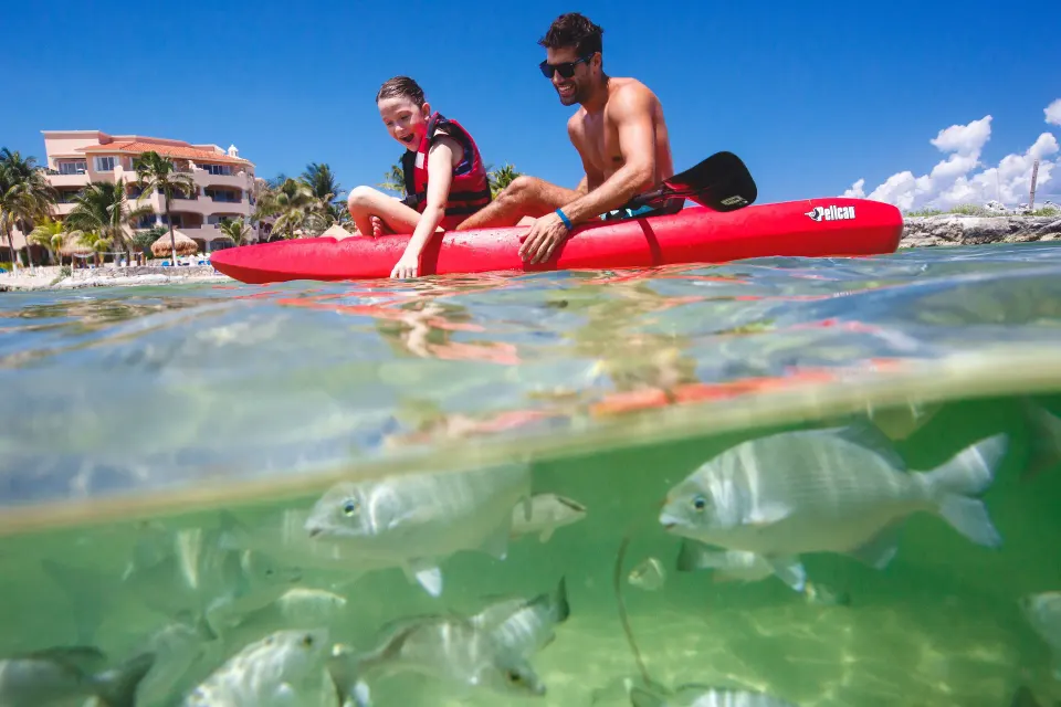 Two people kayaking over clear water with fish visible at Catalonia Riviera Maya Resort and Spa