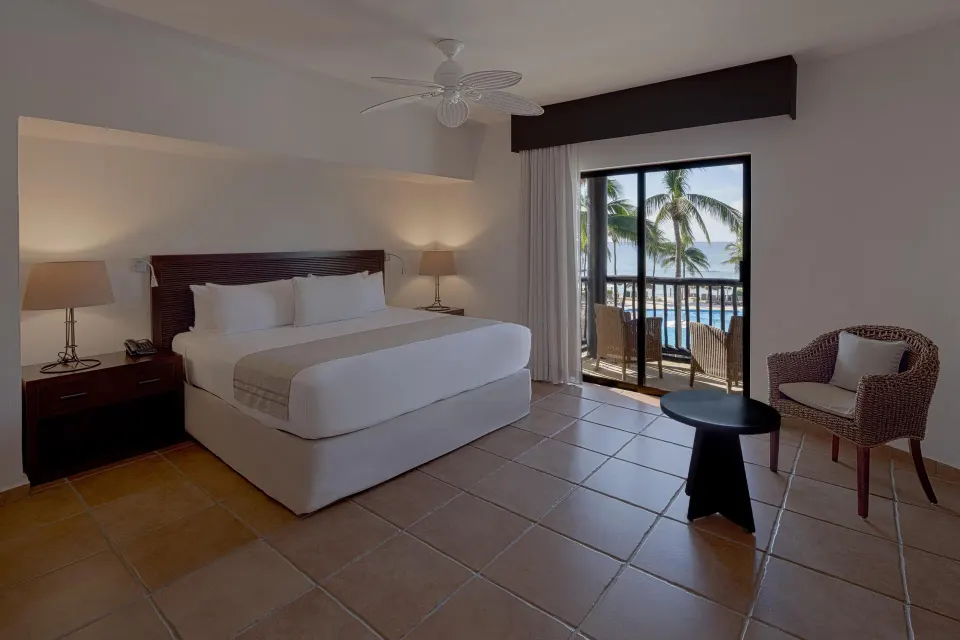 King bed and balcony with palm trees and ocean glimpse at Catalonia Riviera Maya Resort and Spa