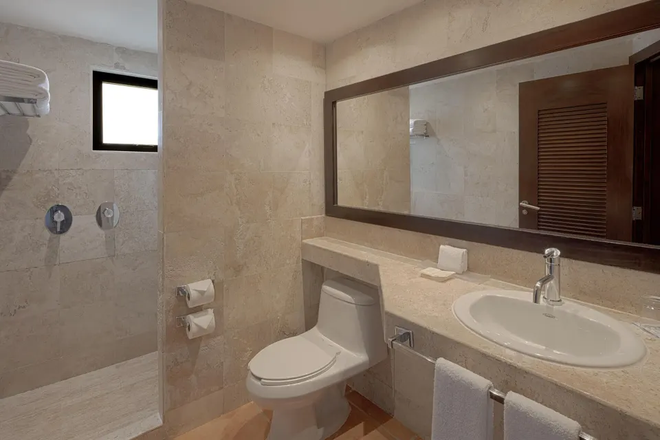 Marble-tiled bathroom with walk-in shower and vanity in a guest room at Catalonia Riviera Maya Resort and Spa