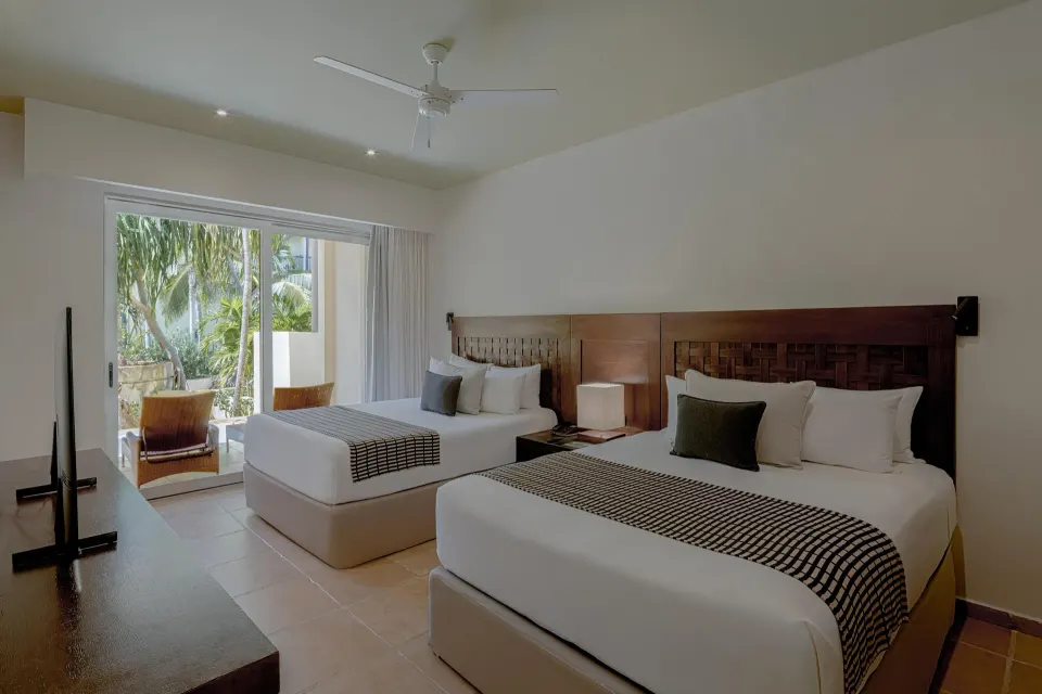 Twin-bed guest room with patio doors opening to greenery at Catalonia Riviera Maya Resort and Spa