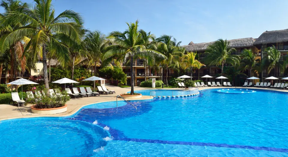 Large resort pool with loungers and palm trees at Catalonia Riviera Maya Resort and Spa