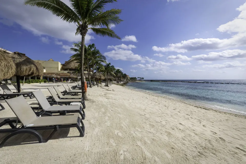 Sandy shoreline with loungers and calm sea at Catalonia Riviera Maya Resort and Spa