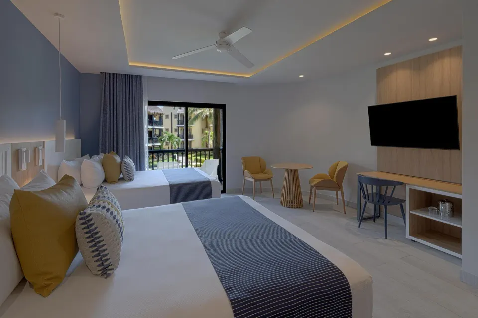 Two beds, balcony with greenery, and seating area in a contemporary room at Catalonia Riviera Maya Resort and Spa