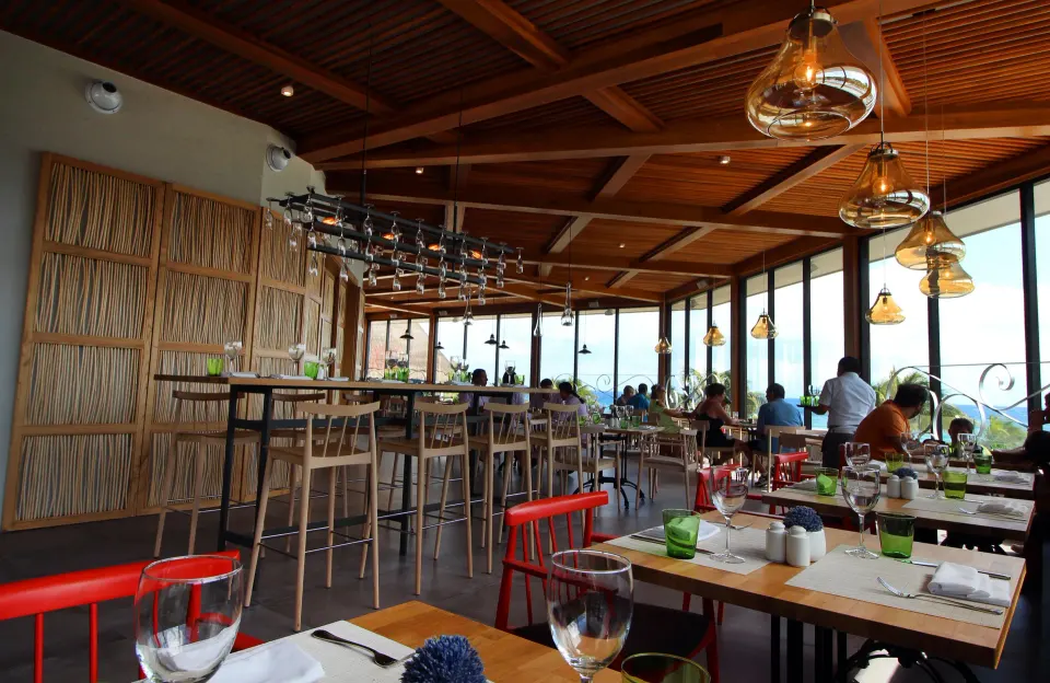 Bright modern restaurant interior with tall bar stools and ocean views at Catalonia Riviera Maya Resort and Spa
