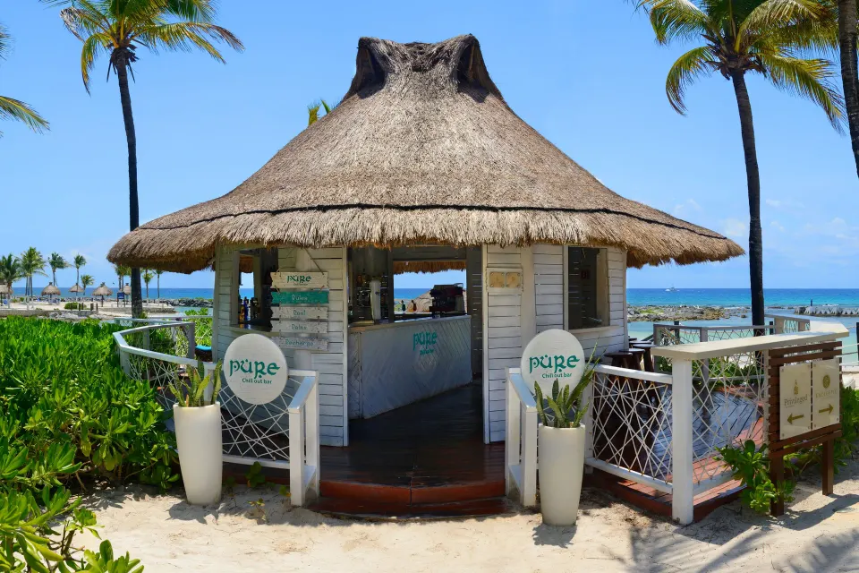 Thatched beach kiosk with signage and ocean backdrop at Catalonia Riviera Maya Resort and Spa