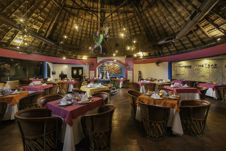 Thatched-roof dining room with decorated tables at Catalonia Riviera Maya Resort and Spa