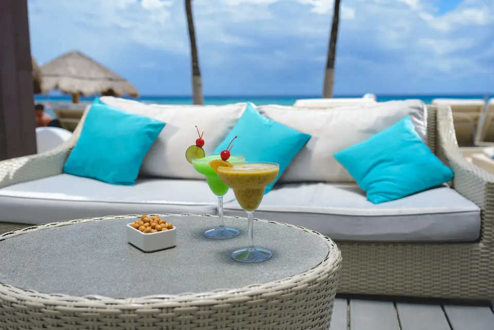 Two tropical cocktails on a table by a seaside lounge at Catalonia Riviera Maya Resort and Spa