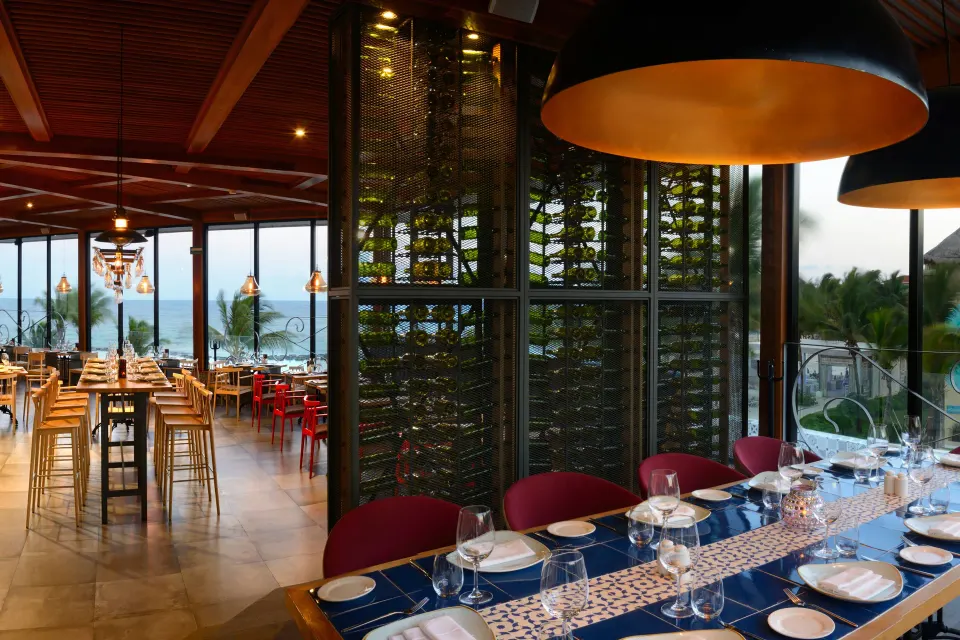 Ocean-view dining area with wine display and pendant lights at Catalonia Riviera Maya Resort and Spa
