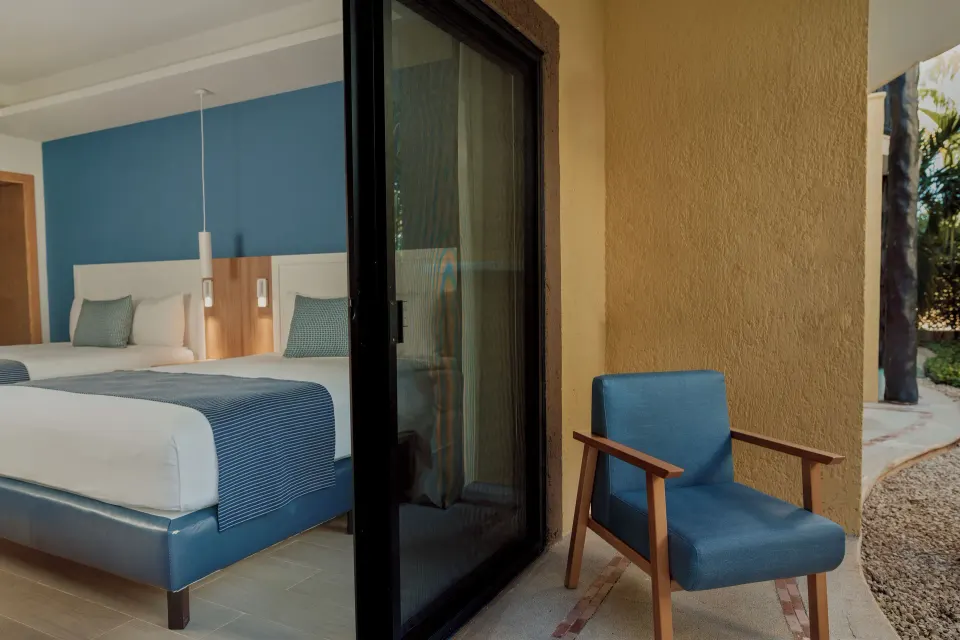 Sliding glass door and patio chair outside a Premium Deluxe Room at Catalonia Riviera Maya Resort and Spa