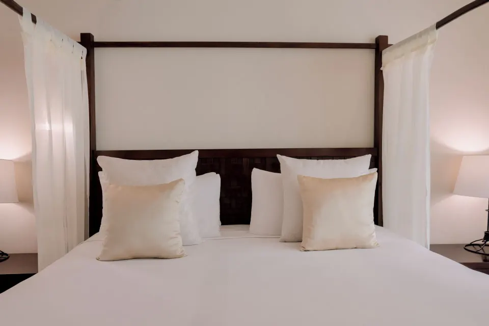 Head-on view of a four-poster king bed with bedside lamps in a Privileged Romance Room at Catalonia Riviera Maya Resort and S