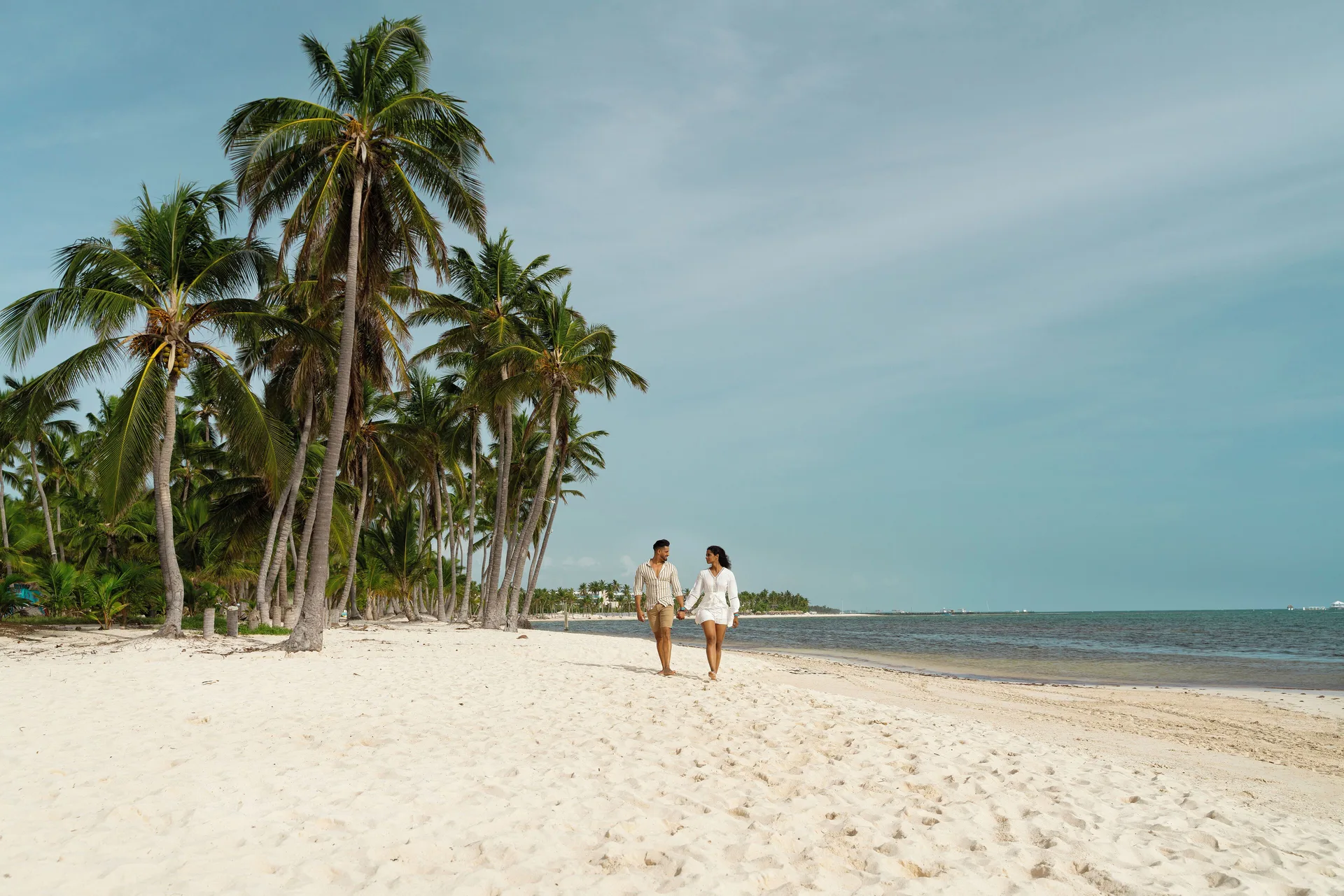 Couple walking along the palm-lined beach at Catalonia Royal Bavaro.