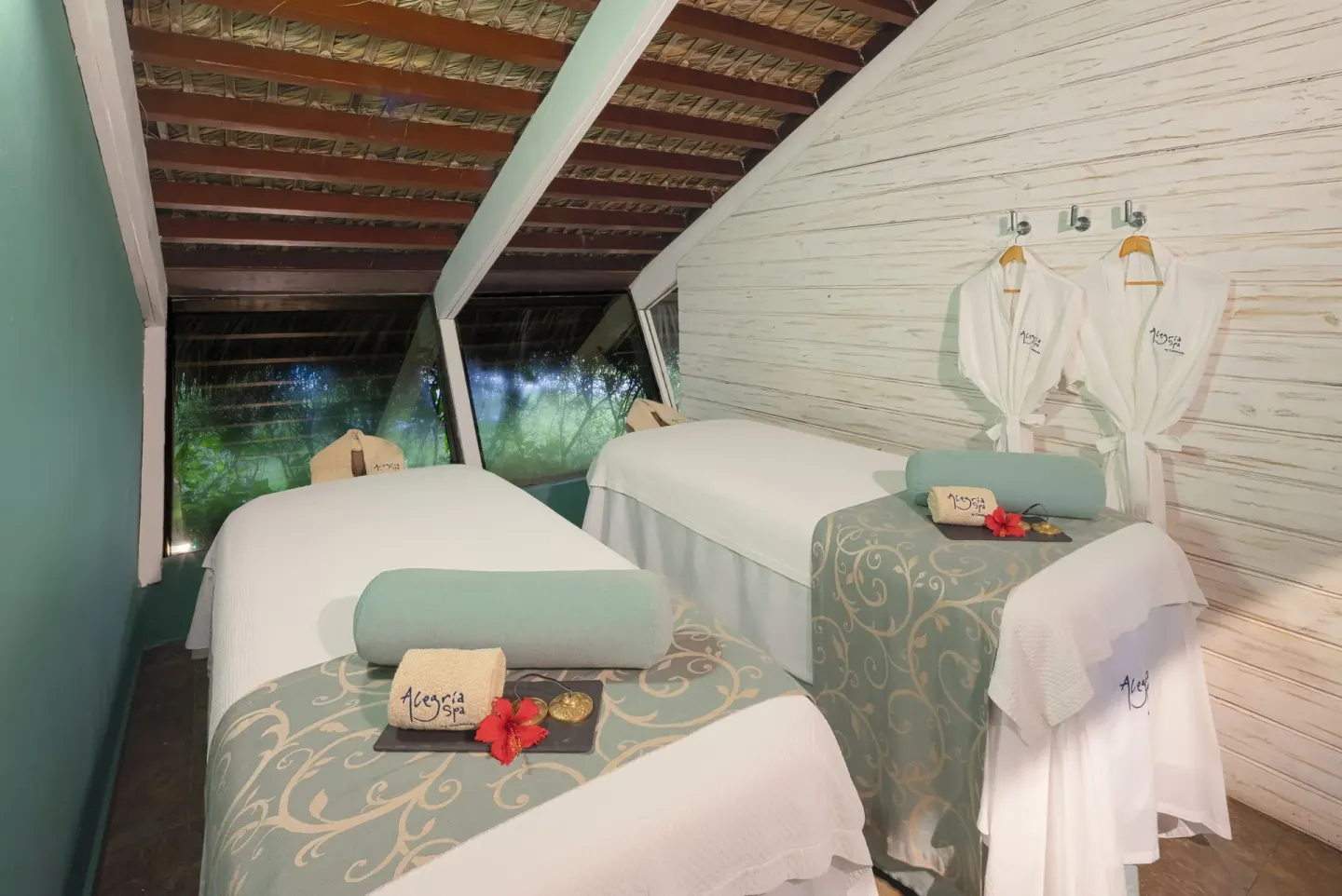 Spa treatment room with two massage beds and robes at Catalonia Royal Bavaro.