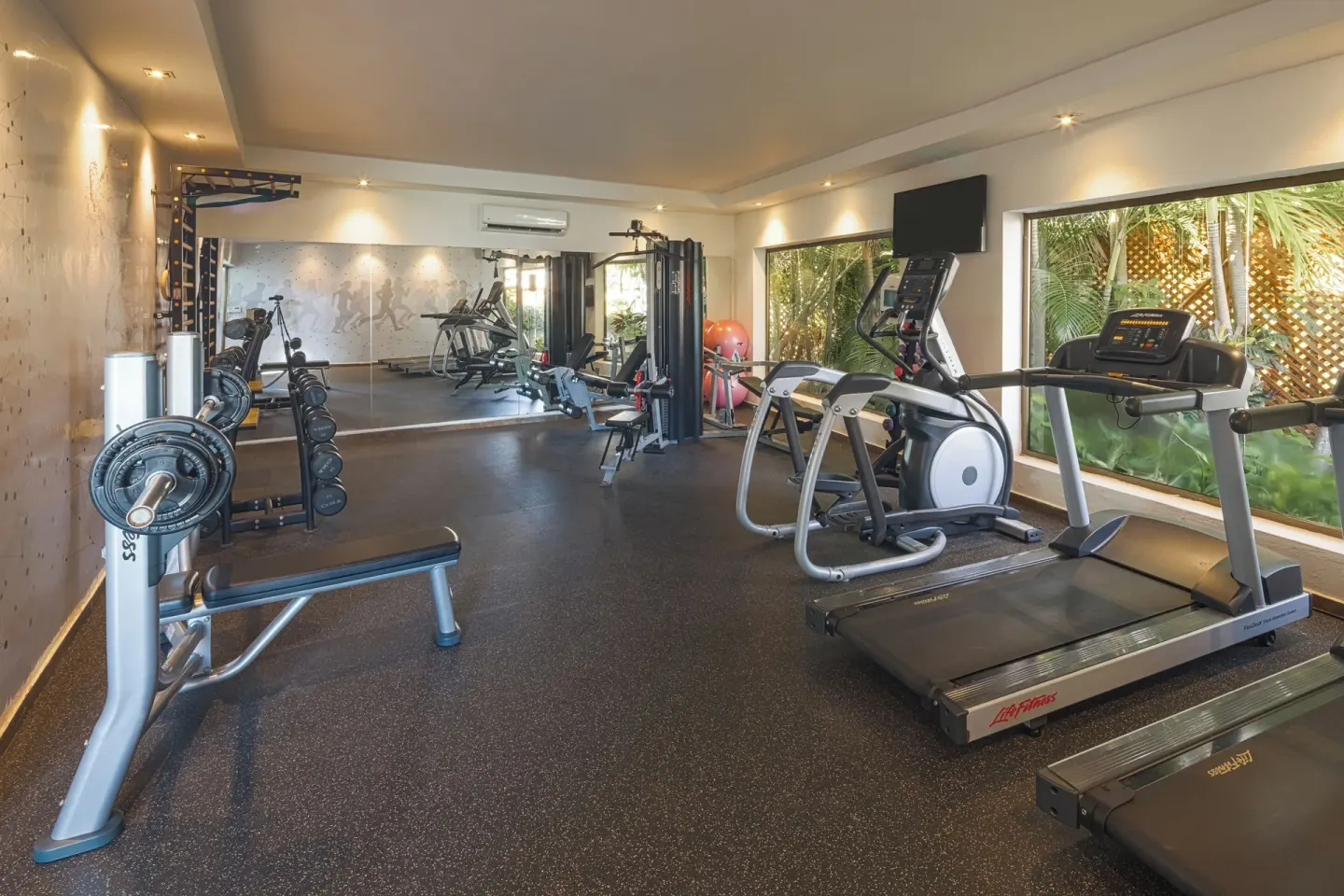 Fitness room with treadmills, weights and large windows at Catalonia Royal Bavaro.