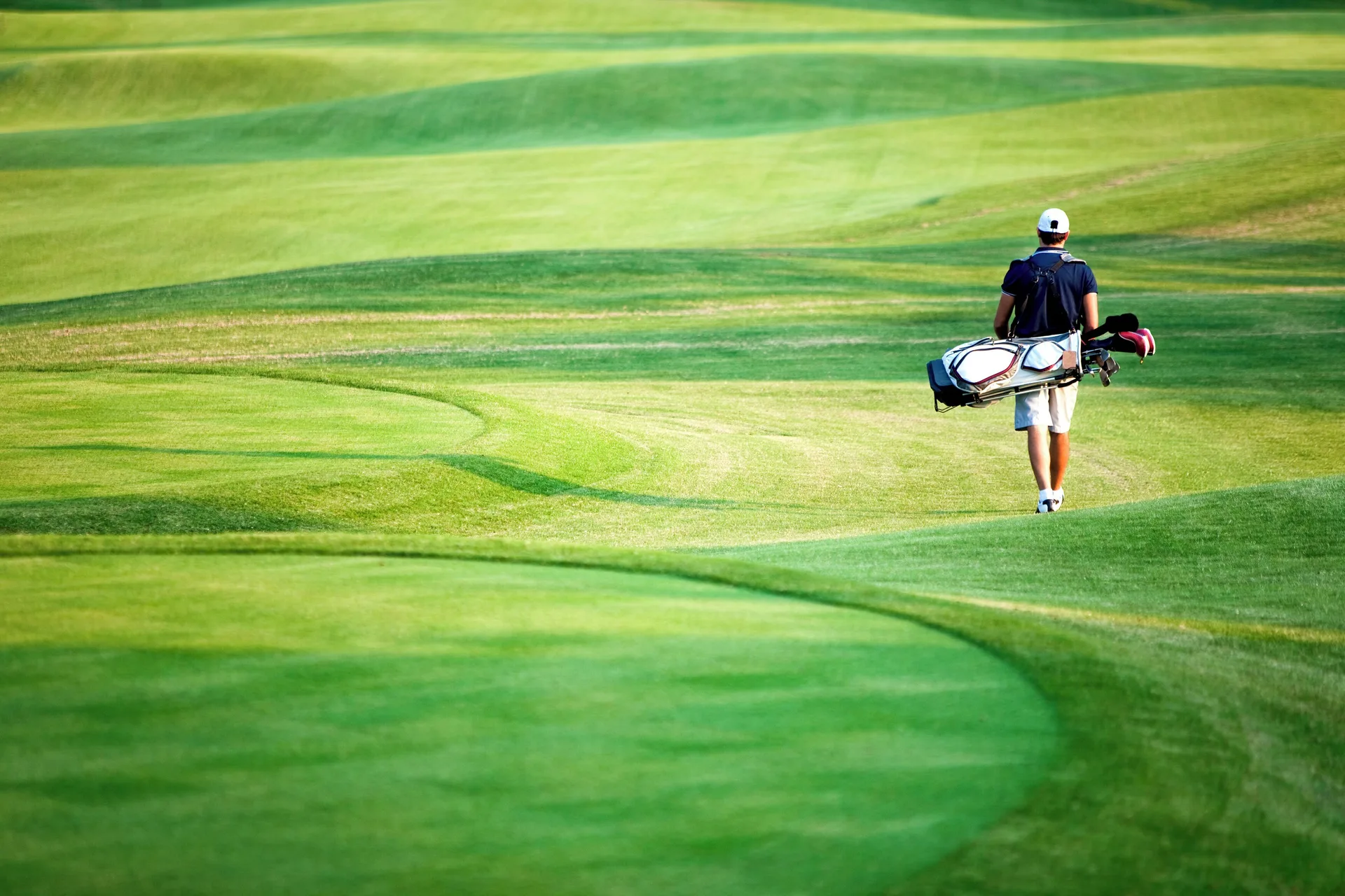 A golfer walks across a green fairway near Catalonia Royal Bavaro.