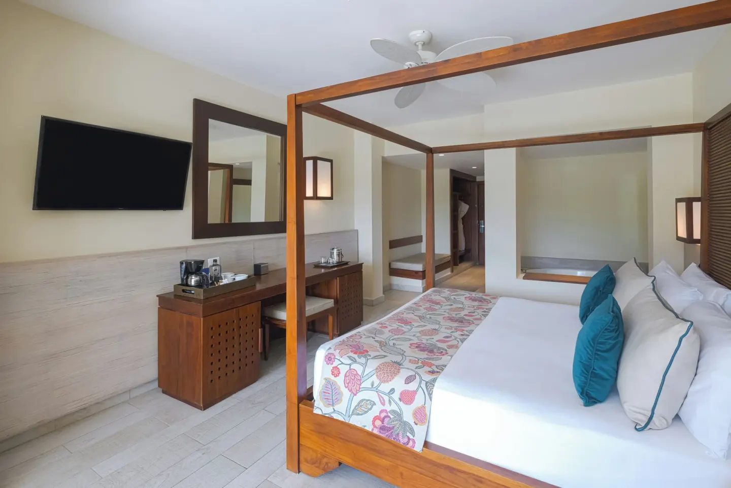 Four-poster king bed, desk, TV, and soaking tub area at Catalonia Royal Bavaro.