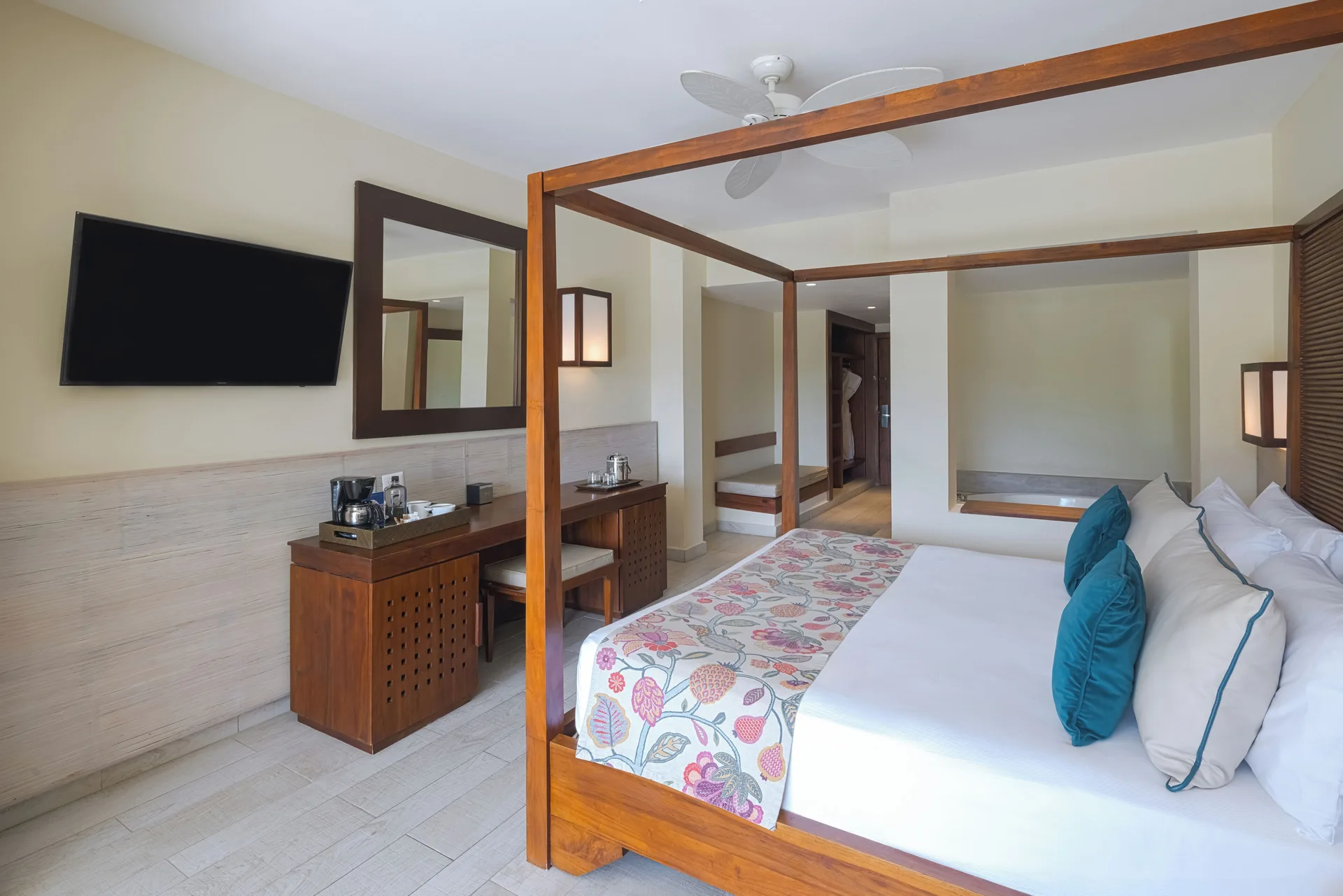 Four-poster king bed, desk, TV, and soaking tub area at Catalonia Royal Bavaro.