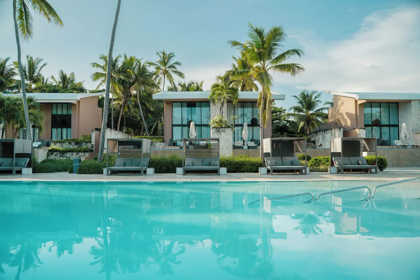 Poolside loungers, palms and low resort buildings at Catalonia Royal Bavaro.