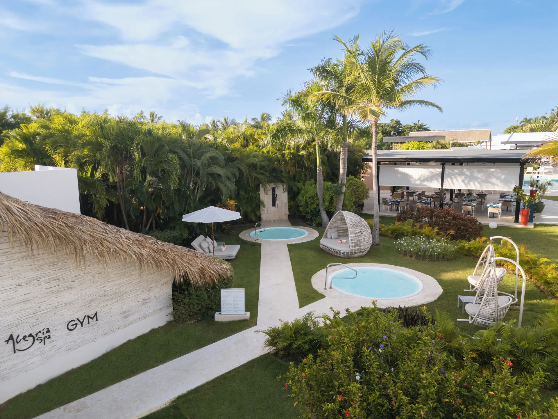 Garden spa area with plunge pools, hanging chairs and gym sign at Catalonia Royal Bavaro.