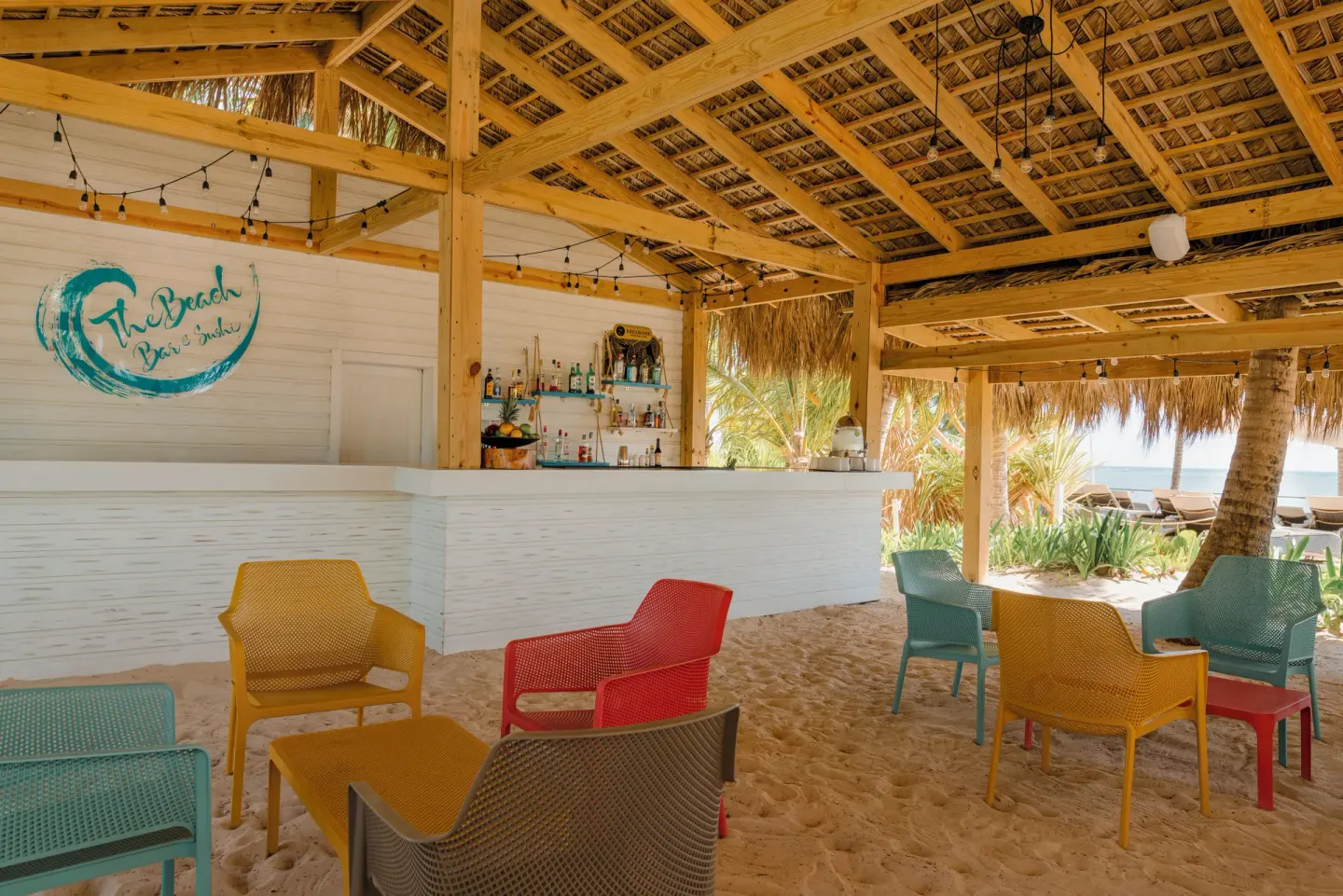 Beach bar seating on the sand under a thatched roof at Catalonia Royal Bavaro.