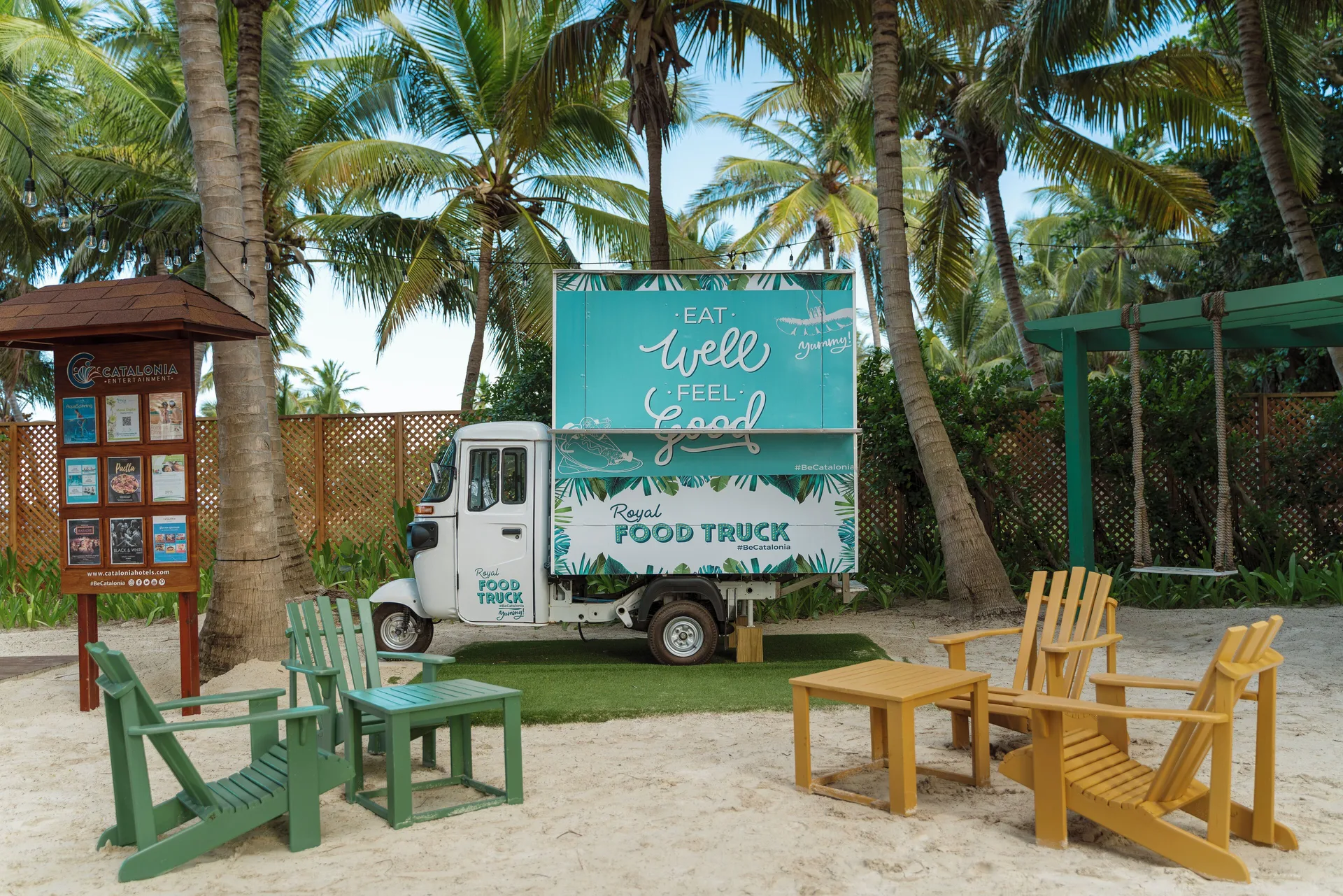 Food truck with colorful outdoor chairs among palm trees at Catalonia Royal Bavaro.