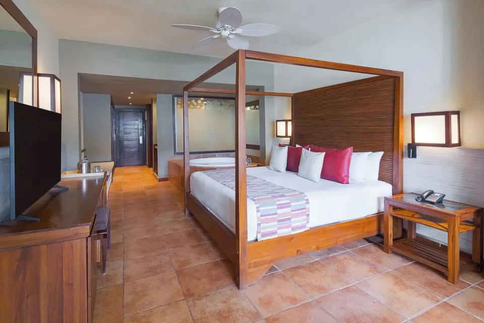 Privileged Deluxe Junior Suite bed area with TV and soaking tub at Catalonia Royal Bavaro.