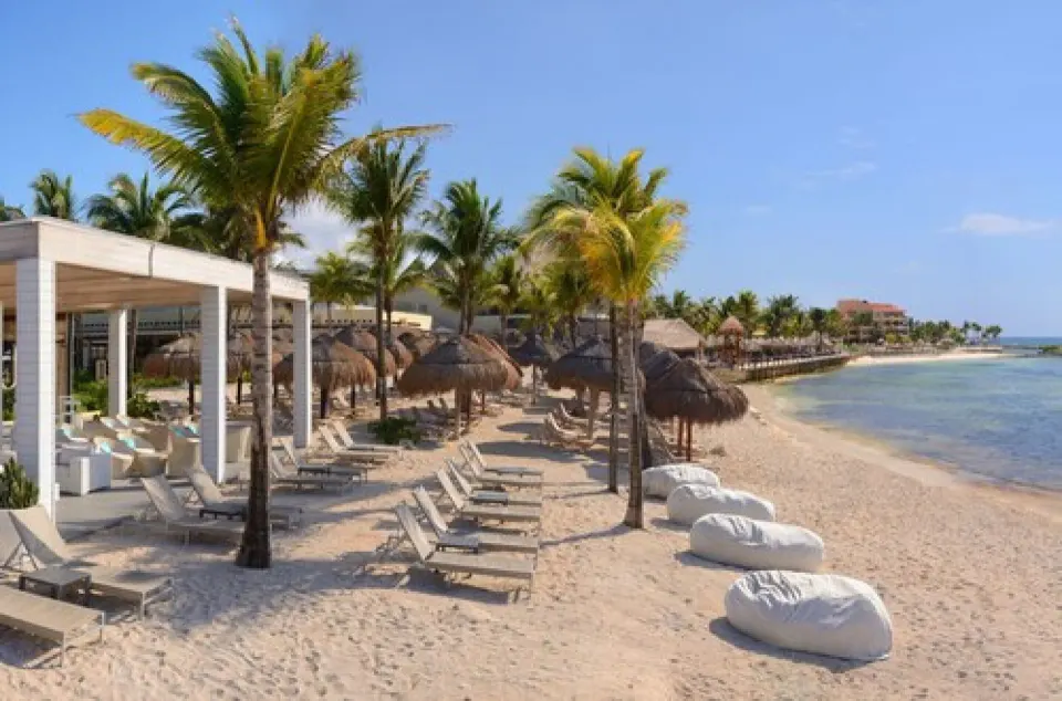 Sandy beach with palapas, loungers and palm trees at Catalonia Yucatan Beach