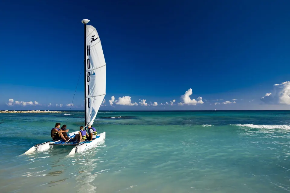 Guests sailing a small catamaran on the sea at Catalonia Yucatan Beach