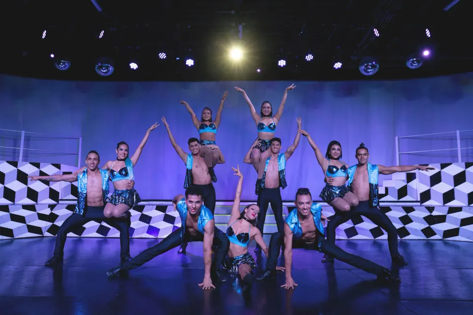 Group of dancers posing onstage in teal costumes at Catalonia Yucatan Beach