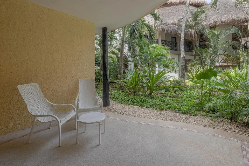 Ground-floor terrace with chairs overlooking landscaped gardens at Catalonia Yucatan Beach.